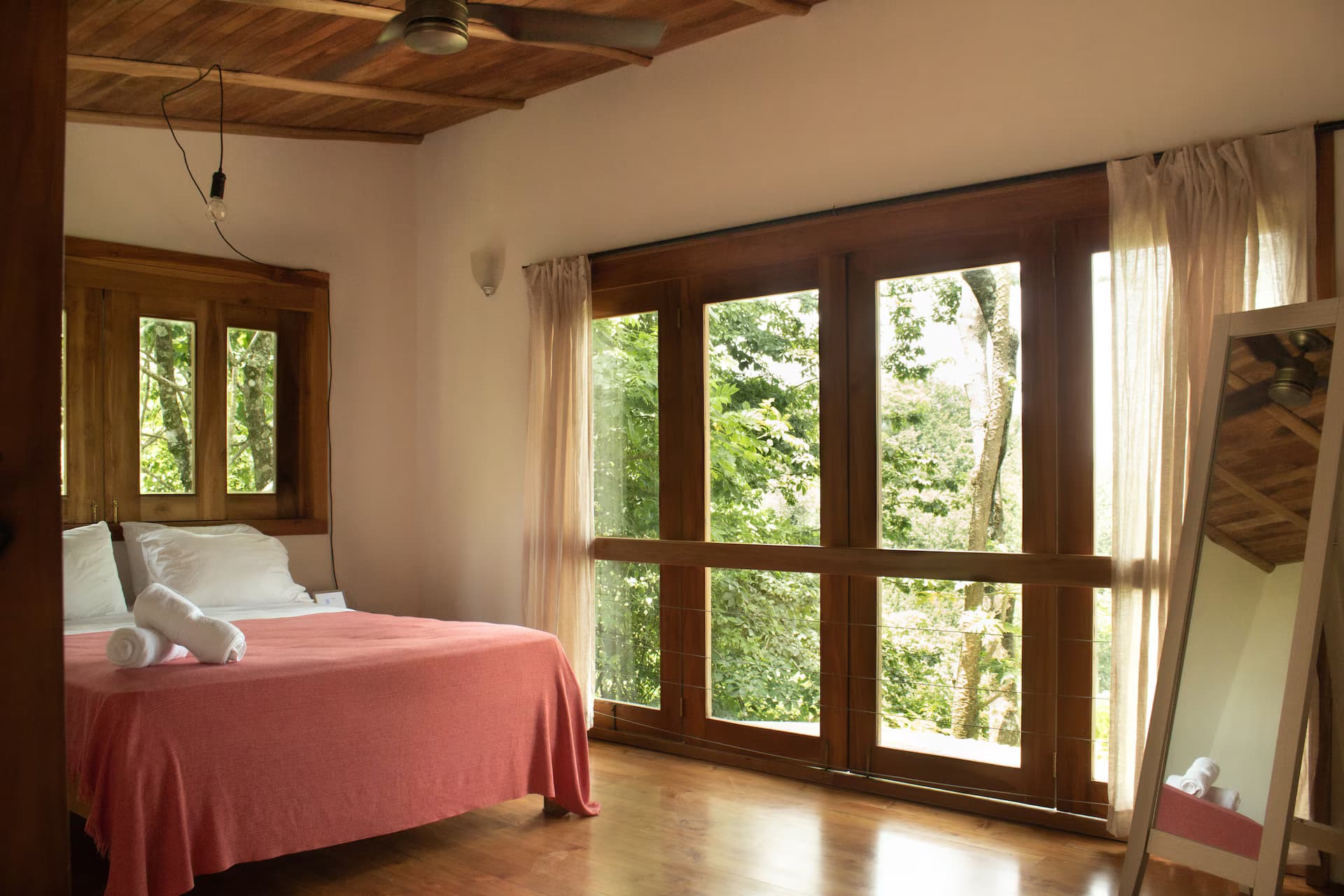 Bedroom with warm coral bedding bathed in sunlight